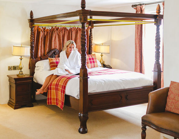 Woman reading on the bed of The Tower Suite at The Bushmills Inn 